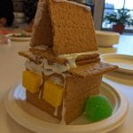 A tall gingerbread house with two yellow starbursts for windows and a green gumdrop on the side as if it was a bush.