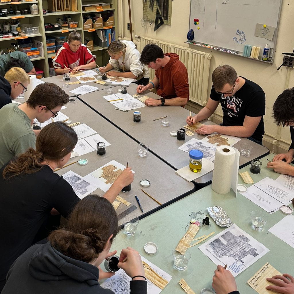 Students in the book arts workshop write on papyrus using reed pens and lamp black ink