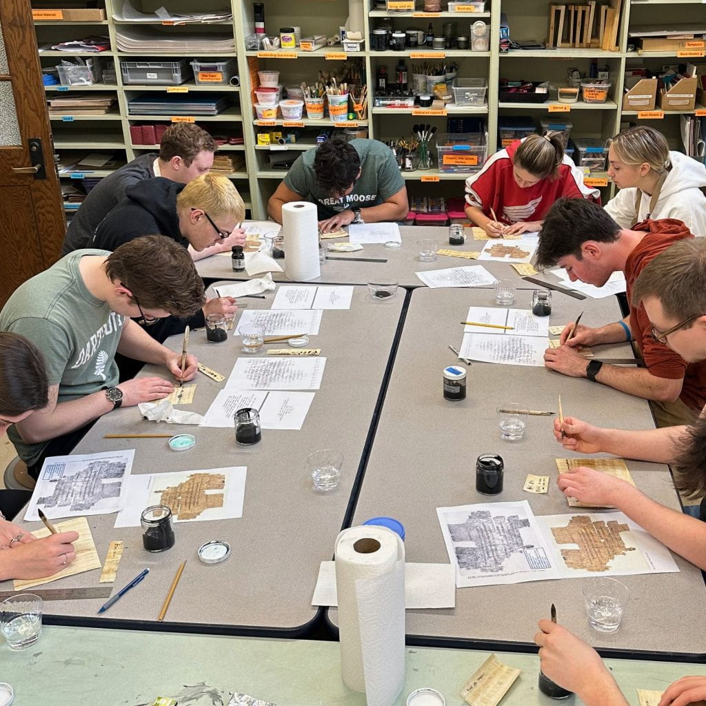 Students in the book arts workshop write on papyrus using reed pens and lamp black ink