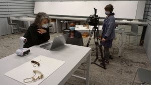 Three people are in a museum smart classroom filming for a virtual class.