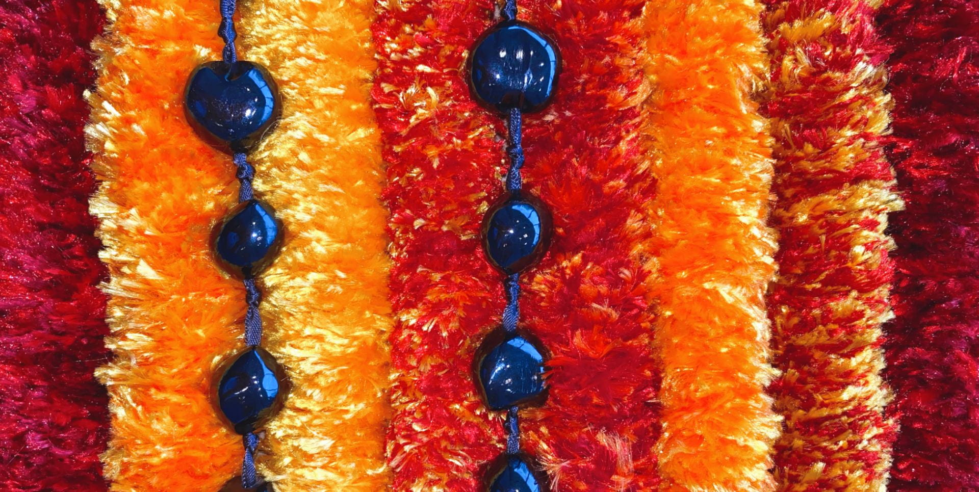 A close up photograph of yarn leis and blue beads.