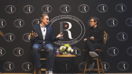 Doug Burgum speaks with the moderator in front of the Rocky step and repeat banner.